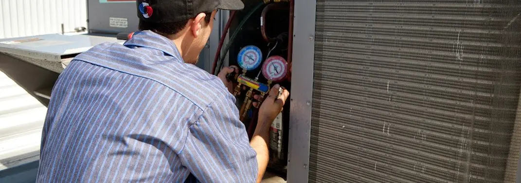 HVAC technician servicing a condenser unit in Forest City